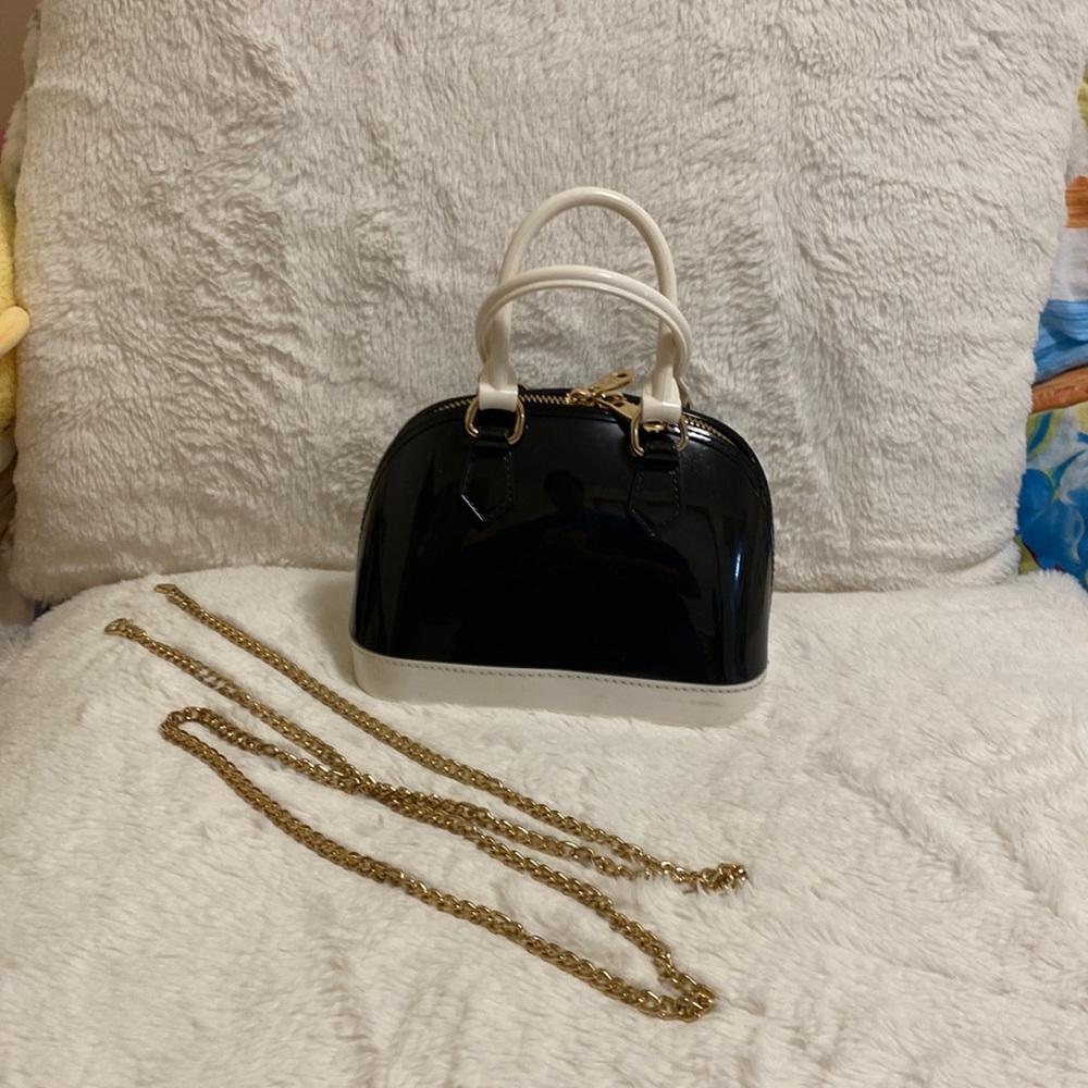Small crossbody/hand bag with gold toned chain straps.